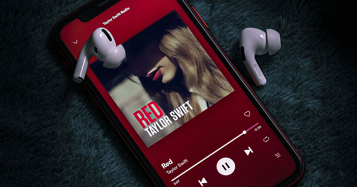 Image of Taylor Swift and her album cover for “Red” on a phone with ear buds.